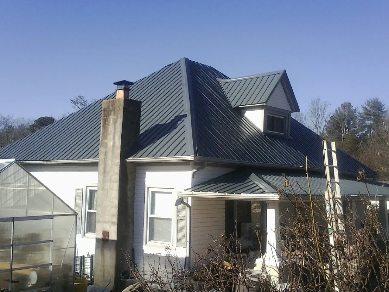 Dark blue standing seam metal roof on a white farmhouse with dormer — Slate & Tile Roof Repair by Roofing Brothers in Falls Village