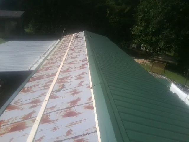 Old rusted panels beside newly installed green metal roofing — Wind Damage Roof Repair by Roofing Brothers in Falls Village