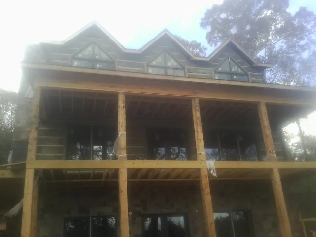 Dormers and porch framing on a large log home under construction — Roof Coating work by our crew in Falls Village