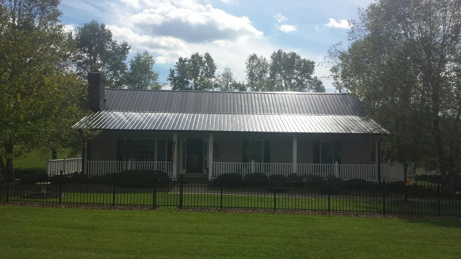 Gray metal roof on a brick ranch with a full width front porch — Gutter Guard Installation work by our crew in Falls Village