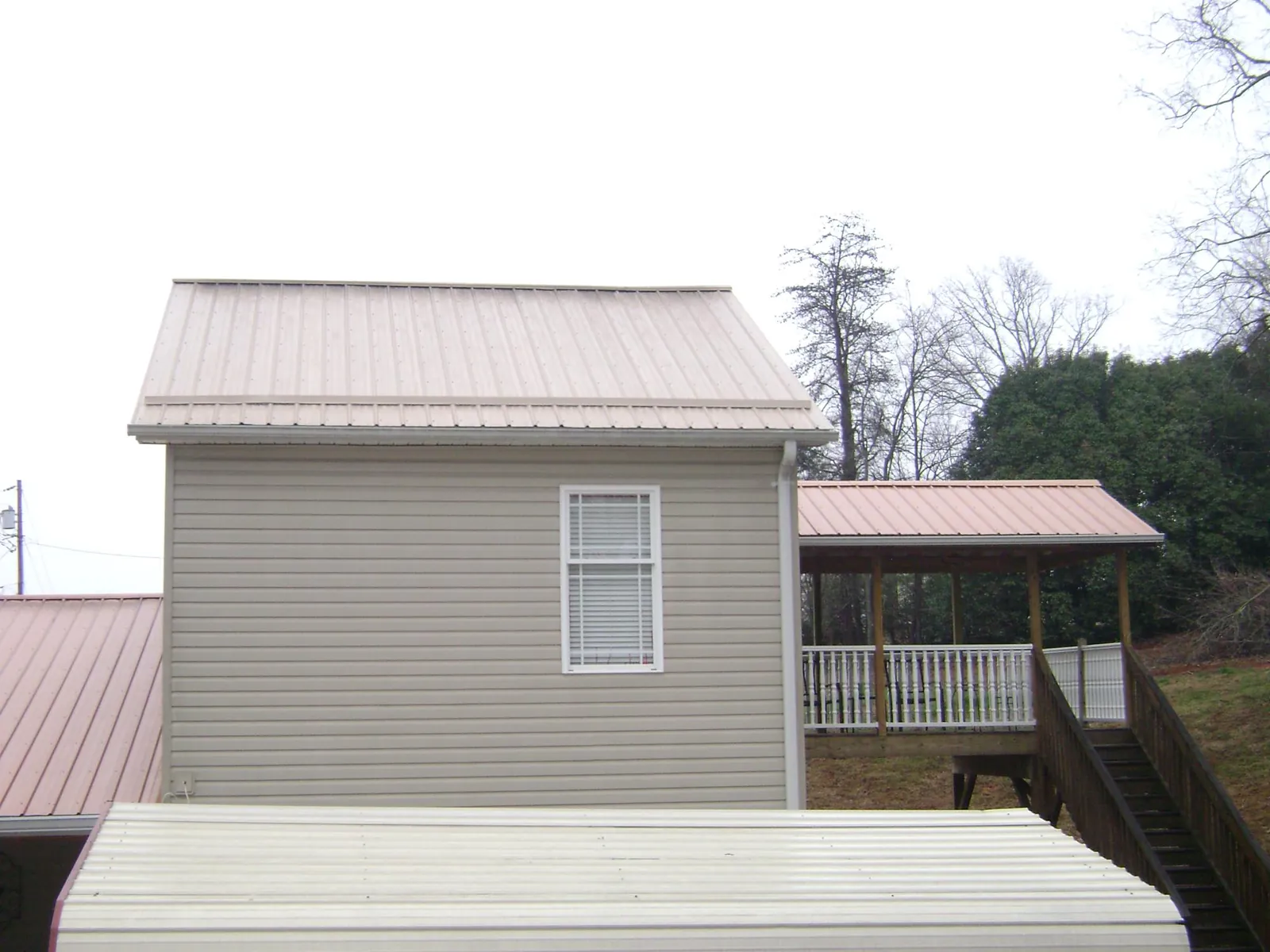 Tan metal roofs on a two story addition and attached porch, from a Roof Replacement job in Falls Village