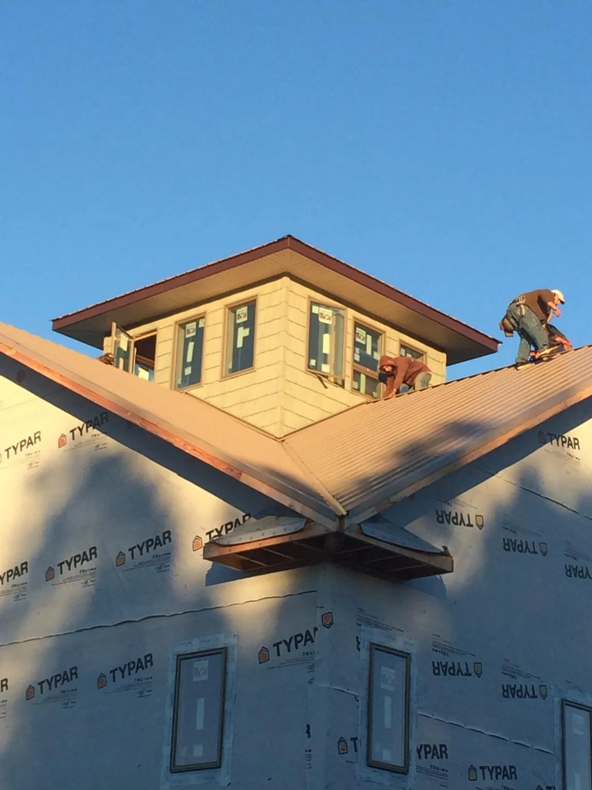 Roofers working around a rooftop cupola on a new metal roof at sunset — Roof Waterproofing in Falls Village by Roofing Brothers